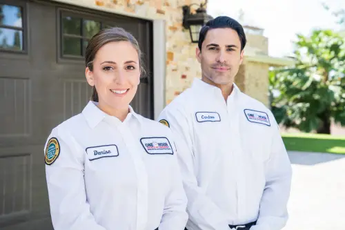 One Hour HVAC techs, Denise and Carlos, standing outside the garage of a beautiful Niceville, FL home