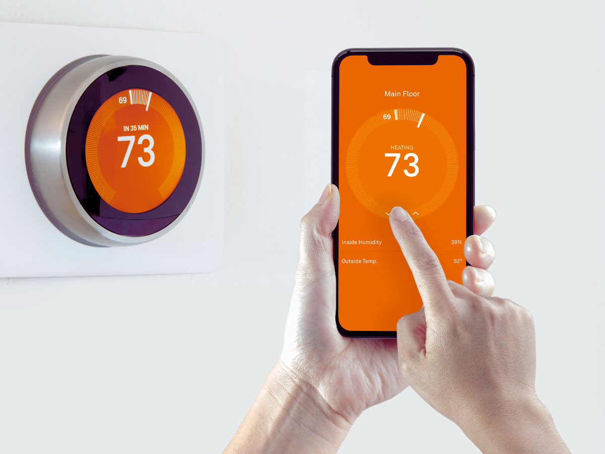 Homeowner adjusting smart thermostat with phone