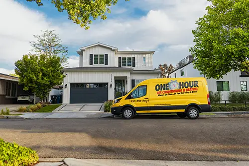 Zoomed out image of a Niceville One Hour Air Conditioning Van in front of a home